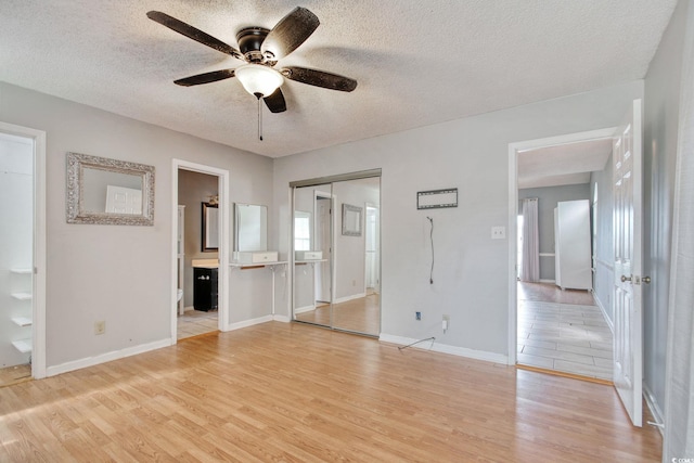 4337 Spa Dr Unit 1309, Little River, SC 29566 - unfurnished bedroom featuring light wood-style flooring, a textured ceiling, connected bathroom, a closet, and a ceiling fan