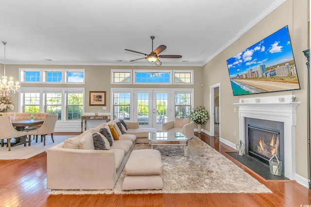 living room featuring a towering ceiling, ornamental molding, hardwood / wood-style floors, and ceiling fan with notable chandelier