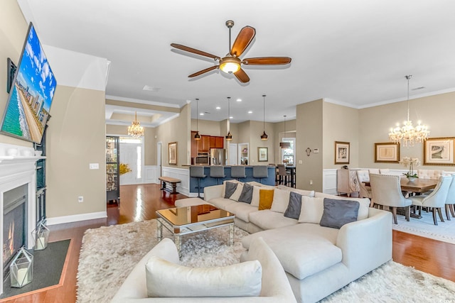 living room with ornamental molding, dark hardwood / wood-style floors, and ceiling fan with notable chandelier