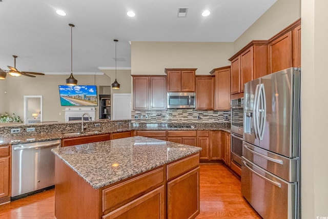 kitchen with sink, a center island, appliances with stainless steel finishes, and light hardwood / wood-style flooring