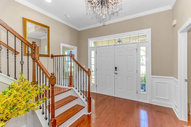 foyer entrance featuring crown molding, wood-type flooring, and a chandelier