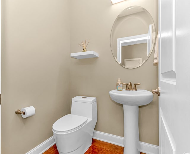 bathroom with toilet, sink, and wood-type flooring