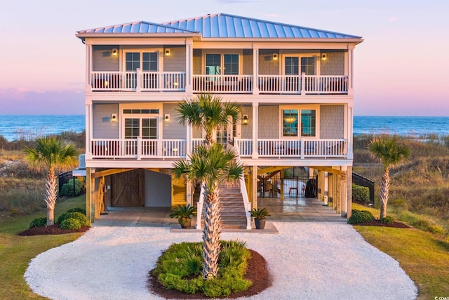 raised beach house featuring a carport, a water view, and a porch