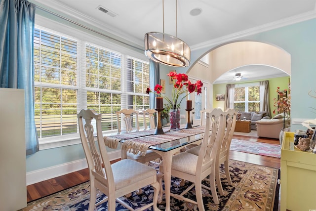 dining space featuring ceiling fan with notable chandelier, wood-type flooring, and crown molding