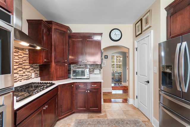 kitchen with appliances with stainless steel finishes, wall chimney exhaust hood, and tasteful backsplash