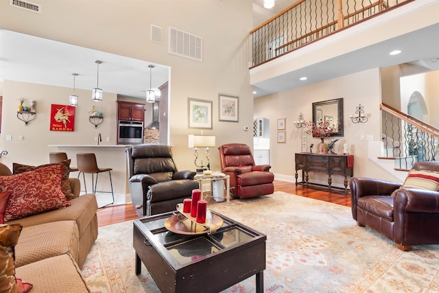 living room featuring a towering ceiling and light hardwood / wood-style flooring