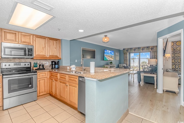 kitchen featuring sink, stainless steel appliances, kitchen peninsula, a textured ceiling, and light wood-type flooring