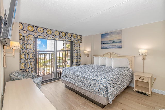 bedroom with access to exterior, light hardwood / wood-style floors, and a textured ceiling