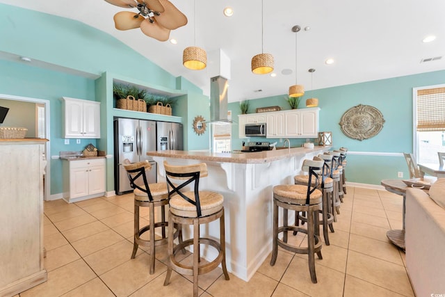 kitchen featuring stainless steel appliances, island range hood, pendant lighting, white cabinets, and lofted ceiling