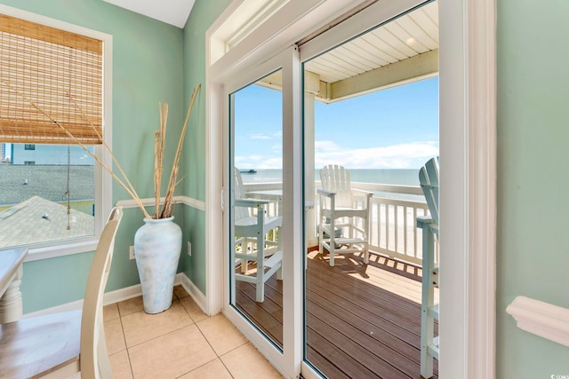 doorway to outside with light tile patterned floors and a water view