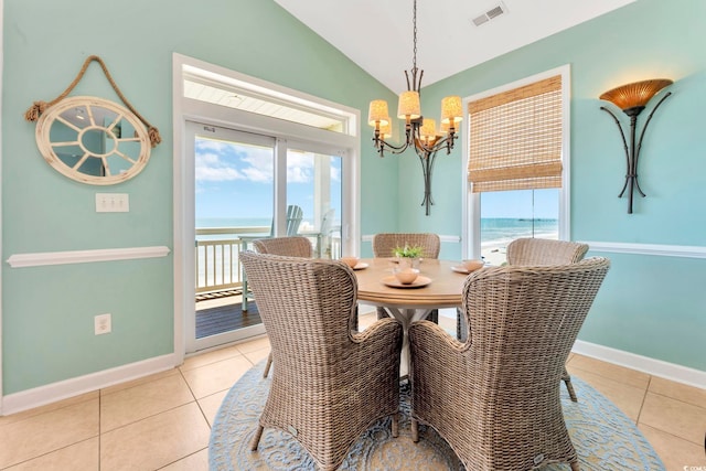 dining space featuring a wealth of natural light, a water view, lofted ceiling, and an inviting chandelier