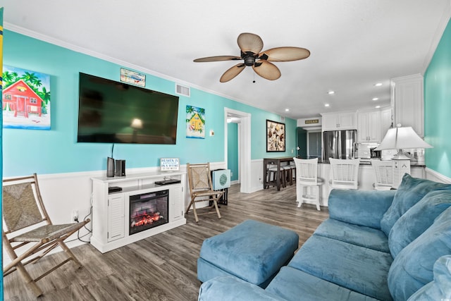 5601 N Ocean Blvd Unit C-305, Myrtle Beach, SC 29577 - living area featuring ceiling fan, a wainscoted wall, a glass covered fireplace, ornamental molding, and dark wood-type flooring