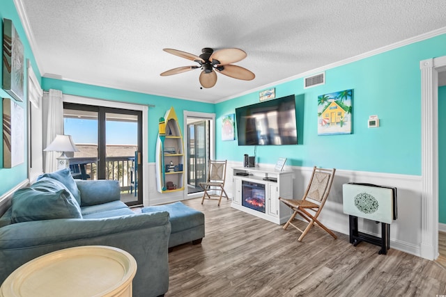 5601 N Ocean Blvd Unit C-305, Myrtle Beach, SC 29577 - living area featuring a ceiling fan, a glass covered fireplace, a textured ceiling, wood finished floors, and crown molding