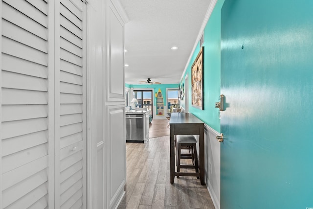 corridor featuring light wood-type flooring and ornamental molding