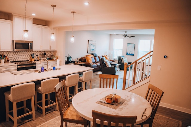 dining area with ceiling fan, sink, and dark hardwood / wood-style flooring