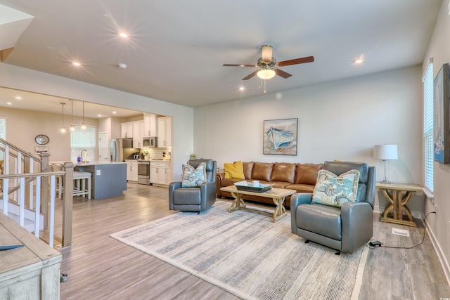 living area featuring ceiling fan, recessed lighting, baseboards, stairway, and light wood finished floors