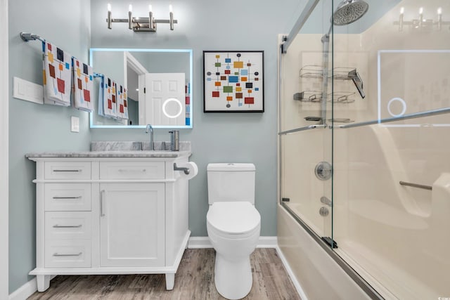 full bathroom featuring hardwood / wood-style floors, shower / bath combination with glass door, vanity, and toilet