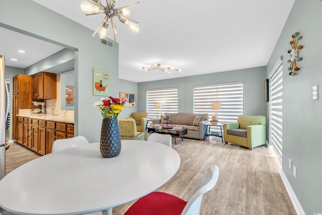 dining space with a notable chandelier and light hardwood / wood-style floors