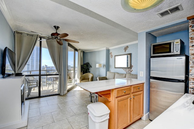 kitchen with a textured ceiling, stainless steel appliances, ceiling fan, crown molding, and light tile patterned floors