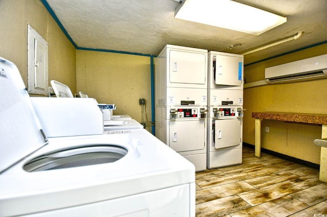 clothes washing area featuring a wall mounted AC, light hardwood / wood-style flooring, and stacked washer and clothes dryer