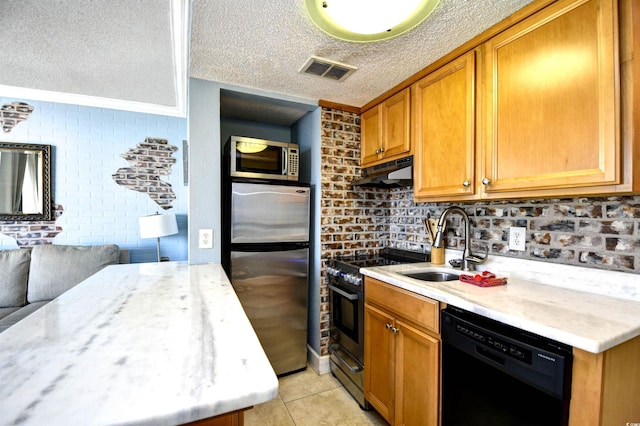 kitchen featuring sink, stainless steel appliances, brick wall, a textured ceiling, and light tile patterned floors