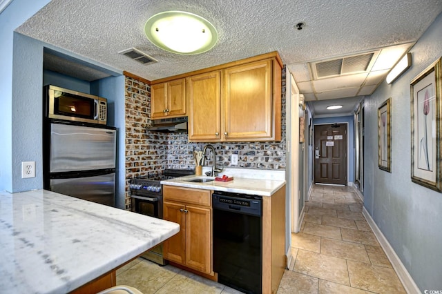 kitchen with tasteful backsplash, a textured ceiling, stainless steel appliances, sink, and light tile patterned floors