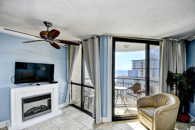 living room with floor to ceiling windows, a water view, ceiling fan, light tile patterned floors, and a textured ceiling