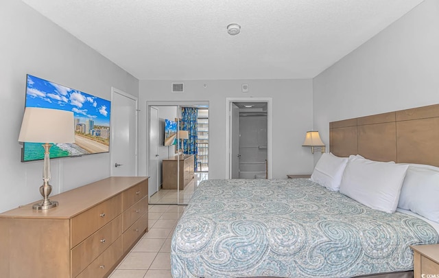 bedroom featuring light tile patterned floors, a textured ceiling, and a closet