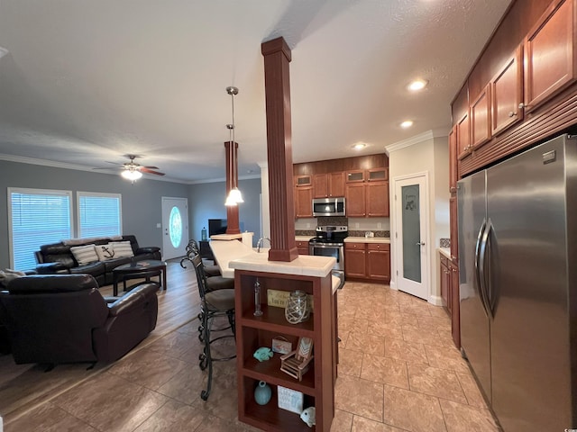 kitchen with stainless steel appliances, hanging light fixtures, a breakfast bar area, ornamental molding, and ceiling fan