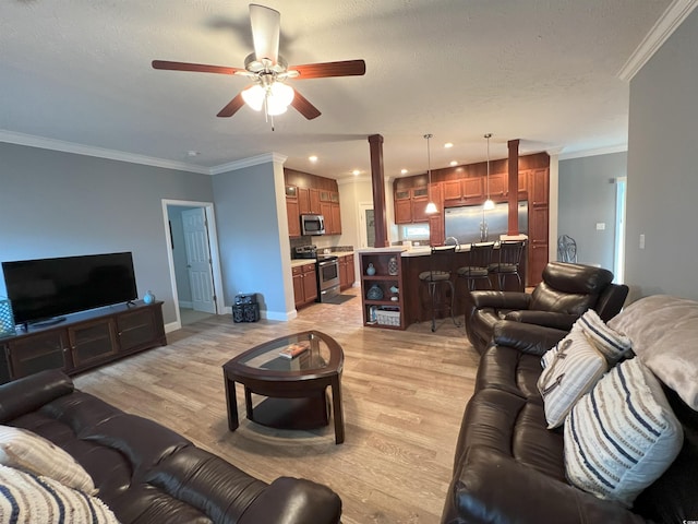 living room featuring light wood-type flooring, a textured ceiling, ceiling fan, and crown molding