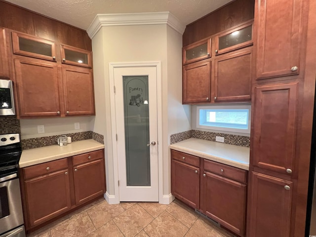 kitchen with crown molding, light tile patterned floors, a textured ceiling, and appliances with stainless steel finishes