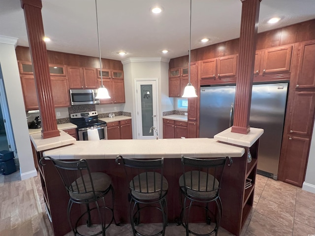 kitchen featuring stainless steel appliances, ornate columns, and pendant lighting