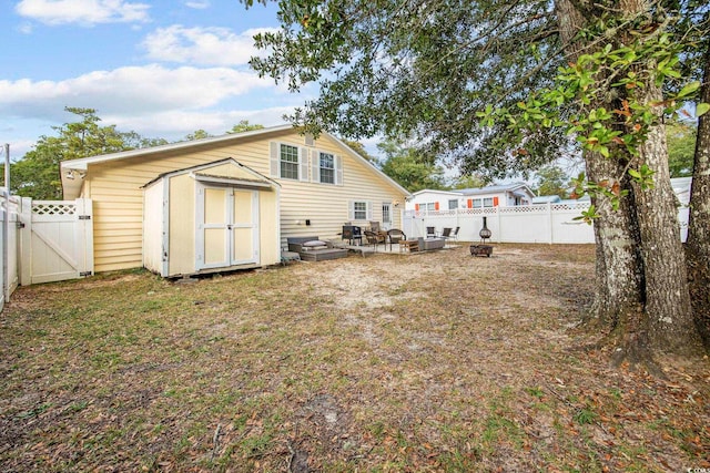 rear view of property with a fire pit and a storage unit