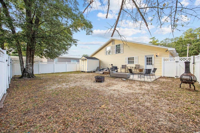 rear view of property featuring a patio area, a fire pit, and a storage unit