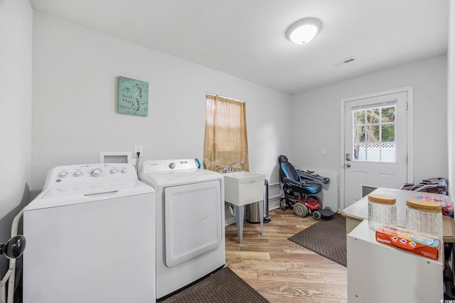 laundry area featuring washer and clothes dryer, light wood-type flooring, and sink