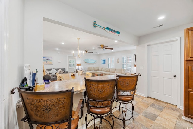 kitchen featuring a kitchen breakfast bar, kitchen peninsula, and ceiling fan with notable chandelier