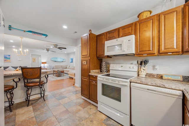 kitchen with ceiling fan with notable chandelier, white appliances, hanging light fixtures, and light hardwood / wood-style flooring