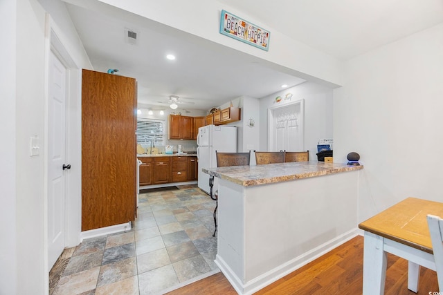 kitchen featuring kitchen peninsula, ceiling fan, light hardwood / wood-style flooring, and white refrigerator