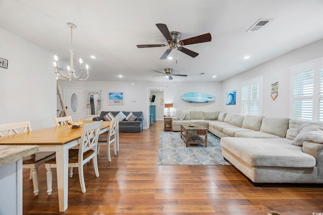 living room with ceiling fan with notable chandelier and dark hardwood / wood-style floors