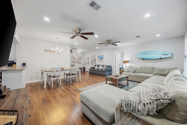 living room with hardwood / wood-style floors and ceiling fan with notable chandelier