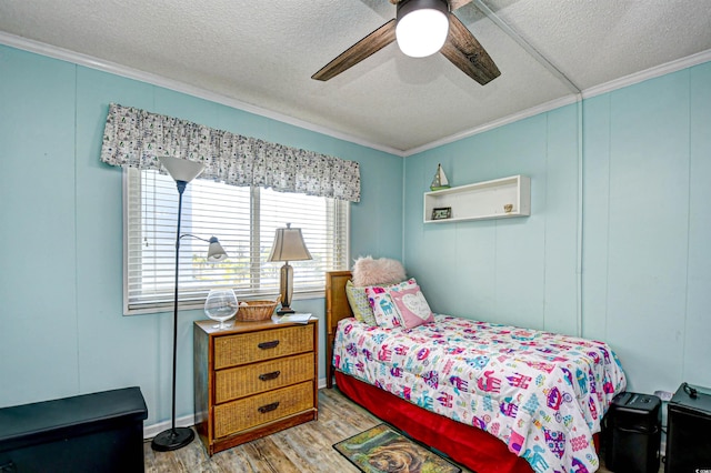 bedroom with ornamental molding, ceiling fan, light wood-type flooring, and a textured ceiling