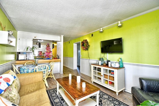 living room featuring crown molding, hardwood / wood-style floors, and a textured ceiling