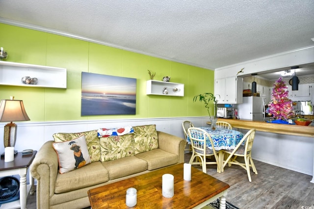 living room with hardwood / wood-style floors, ornamental molding, and a textured ceiling