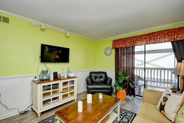 living room featuring ornamental molding, hardwood / wood-style flooring, and a textured ceiling