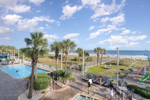 view of pool with a patio, a water view, and a beach view