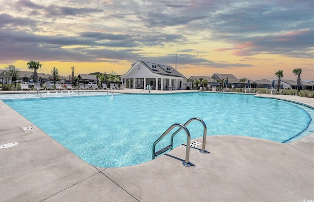 pool at dusk featuring a patio