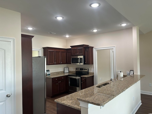 kitchen featuring stainless steel appliances, a center island with sink, sink, a kitchen bar, and dark hardwood / wood-style floors