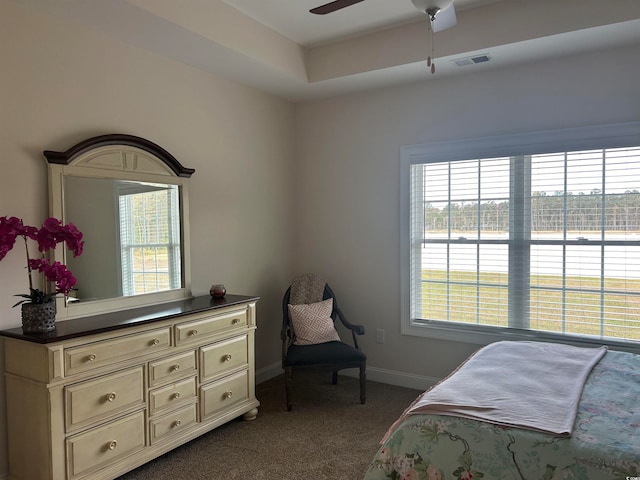 bedroom with multiple windows, dark carpet, and ceiling fan