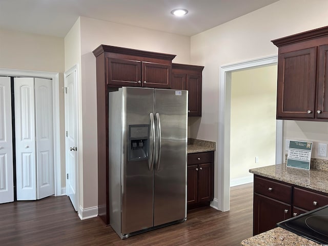 kitchen with dark brown cabinetry, stainless steel refrigerator with ice dispenser, light stone countertops, and dark hardwood / wood-style flooring