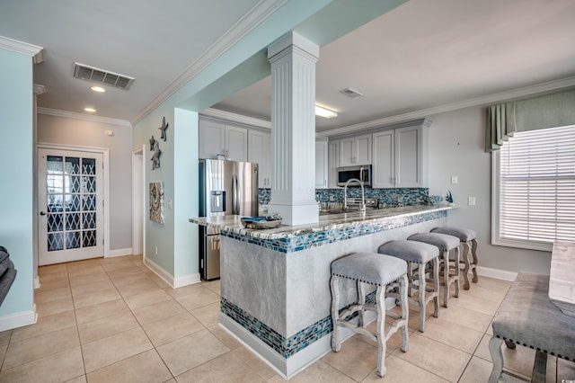 kitchen with stainless steel appliances, light tile patterned floors, gray cabinets, decorative columns, and kitchen peninsula